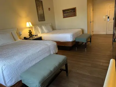 a hotel room with two beds and a chair at Rocklin Park Hotel, Trademark Collection by Wyndham in Rocklin