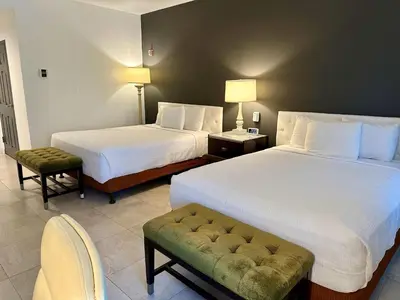 a hotel room with two beds and a chair at Rocklin Park Hotel, Trademark Collection by Wyndham in Rocklin