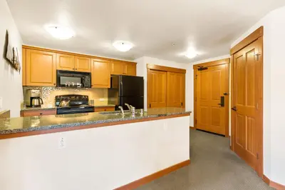 a kitchen with wooden cabinets and a black refrigerator at Village 1401 in Mammoth Lakes