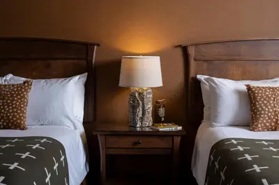 a hotel room with two beds and a lamp on a table at Wayfinder Bishop in Bishop