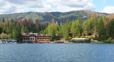 a resort on a lake with a mountain in the background at The Pines Resort & Conference Center in Bass Lake