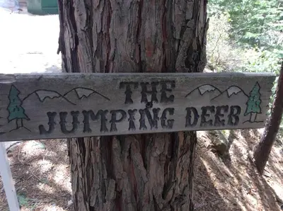 a sign on a tree that reads the jumping deer at Jumping Deer in Yosemite West