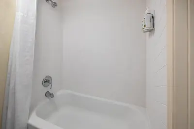 a white bathroom with a tub and a shower at Ramada by Wyndham Merced in Merced