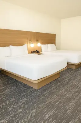 two beds in a hotel room with white sheets at Ramada by Wyndham Merced in Merced