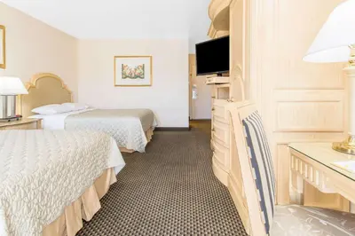 a hotel room with two beds and a flat screen tv at Days Inn by Wyndham Modesto in Modesto