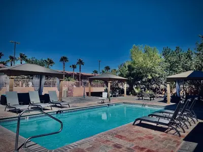 a swimming pool with chairs and umbrellas at Death Valley Inn in Beatty