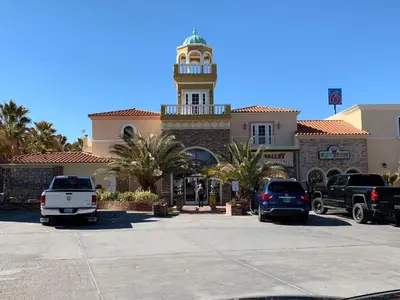 a building with a clock tower and cars parked in a parking lot at Death Valley Inn in Beatty