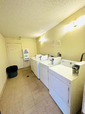 a laundry room with three washing machines in a room at King's Inn Motel in Kingsburg