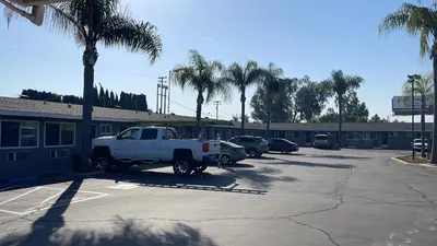 a white truck parked in a parking lot with palm trees at King's Inn Motel in Kingsburg