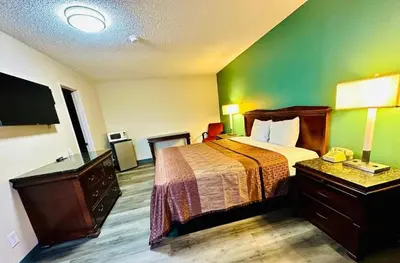 a hotel room with a bed and a flat screen tv at King's Inn Motel in Kingsburg