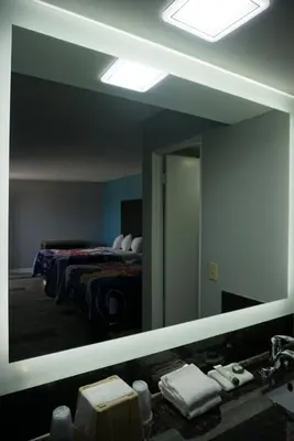a mirror in a bathroom with a bed and a sink at Thunderbird Motel in Bishop