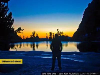 a man standing in front of a lake at sunset at Cozy Muir Cottage - In Town - Pet Friendly in Lone Pine