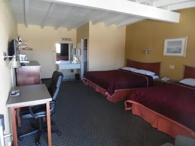 a hotel room with two beds and a desk at Trails Motel in Lone Pine