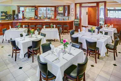 a dining room with white tables and chairs at Lake Natoma Inn in Folsom
