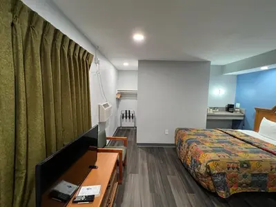 a hotel room with a bed and a desk with a tv at Bishop Elms Motel in Bishop