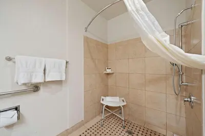 a bathroom with a shower and a stool in it at Best Western Plus Executive Inn & Suites in Manteca