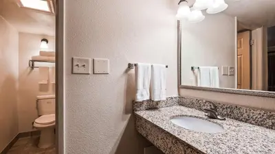 a bathroom with a sink and a mirror and a toilet at Best Western Town House Lodge in Modesto