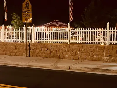 a white picket fence with a street sign next to a sidewalk at Jumping Frog Motel in Angels Camp