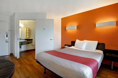 a room with a large bed with an orange wall at Motel 6-Gilroy, CA in Gilroy