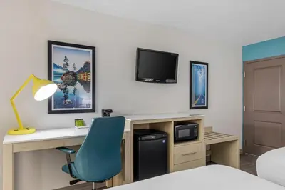 a hotel room with a desk and a blue chair at Hillstone Inn Tulare, an Ascend Collection Hotel in Tulare