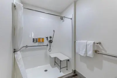 a white bathroom with a shower and a sink at Hillstone Inn Tulare, an Ascend Collection Hotel in Tulare