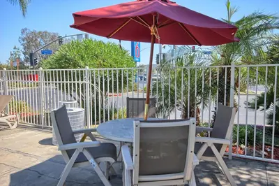a table and chairs with an umbrella on a patio at Motel 6-Tulare, CA in Tulare