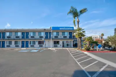 a hotel with a palm tree in a parking lot at Motel 6-Tulare, CA in Tulare