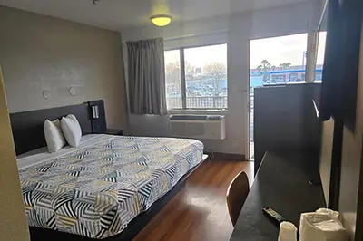 a hotel room with a bed and a large window at Super 8 by Wyndham Tracy in Tracy