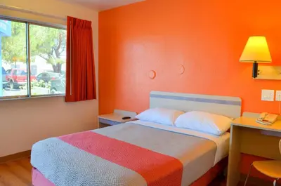 a bedroom with a bed with an orange wall at Motel 6 - Santa Nella, on i-5 in Santa Nella Village