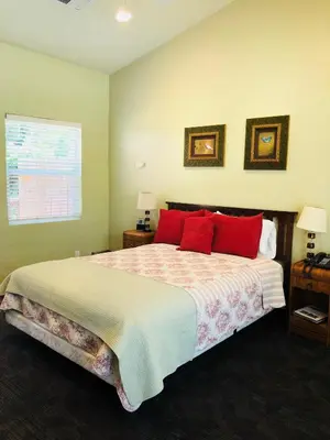 a bedroom with a large bed with red pillows at Queen's Inn By The River in Oakhurst