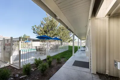 a porch with an umbrella and chairs and a pool at Motel 6-Sparks, NV - Airport - Sparks in Reno
