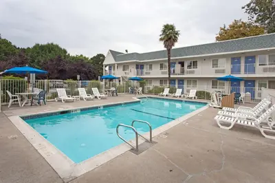 a pool with chairs and umbrellas at a resort at Motel 6-Sacramento, CA - Central in Sacramento