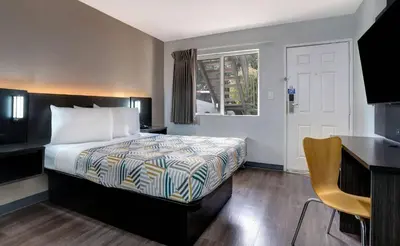 a bedroom with a bed and a desk and a window at Motel 6-Rancho Cordova, CA - Rancho Cordova East in Rancho Cordova