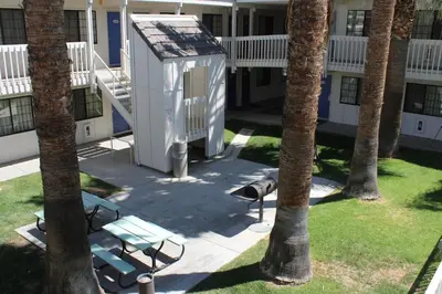 a building with a bench and palm trees in a yard at Motel 6-Coalinga, CA - East in Coalinga