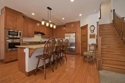 a kitchen with wooden cabinets and a kitchen island with chairs at Timbers 5 4-Bedroom Townhouse Townhouse in Mammoth Lakes
