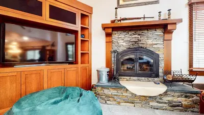 a living room with a stone fireplace with a tv at Timbers 5 4-Bedroom Townhouse Townhouse in Mammoth Lakes