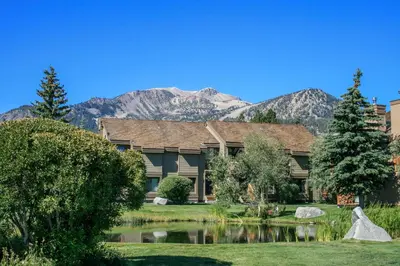 a house with a pond and mountains in the background at Snowcreek 269 Condo in Mammoth Lakes