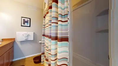a bathroom with a shower with a striped shower curtain at Sierra Manors 8 Townhouse in Mammoth Lakes
