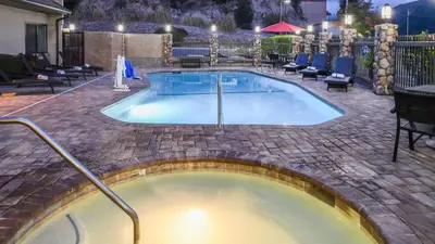 a hot tub in a patio with chairs around it at Yosemite Southgate Hotel & Suites in Oakhurst