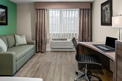 a living room with a couch and a desk with a computer at Yosemite Southgate Hotel & Suites in Oakhurst