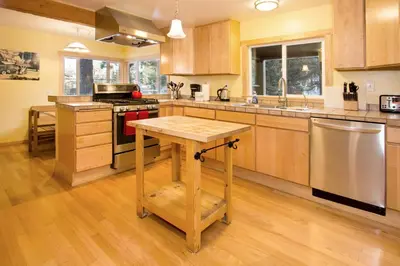 a large kitchen with wooden cabinets and a wooden table at Edelweiss Lodge in Mammoth Lakes