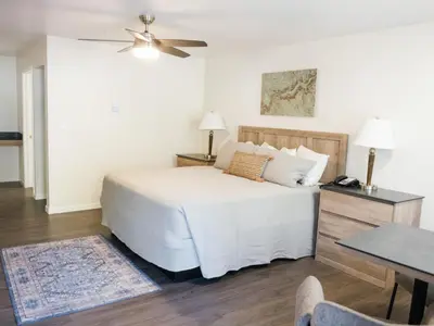 a bedroom with a white bed with a ceiling fan at Cedar Lodge in El Portal