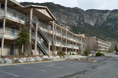a building with a parking lot in front of a mountain at Yosemite View Lodge in El Portal