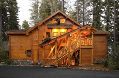 a large wooden cabin in the woods with a large deck at Cottage Inn At Lake Tahoe in Tahoe City