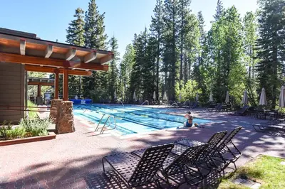 a swimming pool with chairs and a person in the water at Aspen Grove 3090 in Truckee