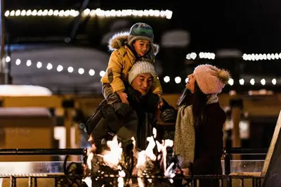 a man with a child on his shoulders next to a fire at Aspen Grove 3090 in Truckee