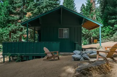 a green cabin with two chairs in front of it at Silver City Mountain Resort in Sequoia National Park