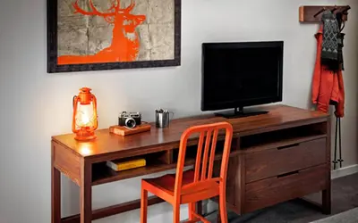 a wooden desk with a television and a orange chair at Basecamp Tahoe South in South Lake Tahoe