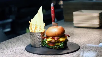 a burger with a knife and a cup of fries at Hotel Mission De Oro in Santa Nella Village