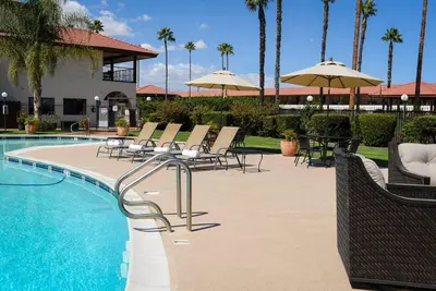 a pool with chairs and umbrellas in a resort at Hotel Mission De Oro in Santa Nella Village